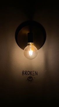 Lampe lyser på væg med det engelske ord "broken"